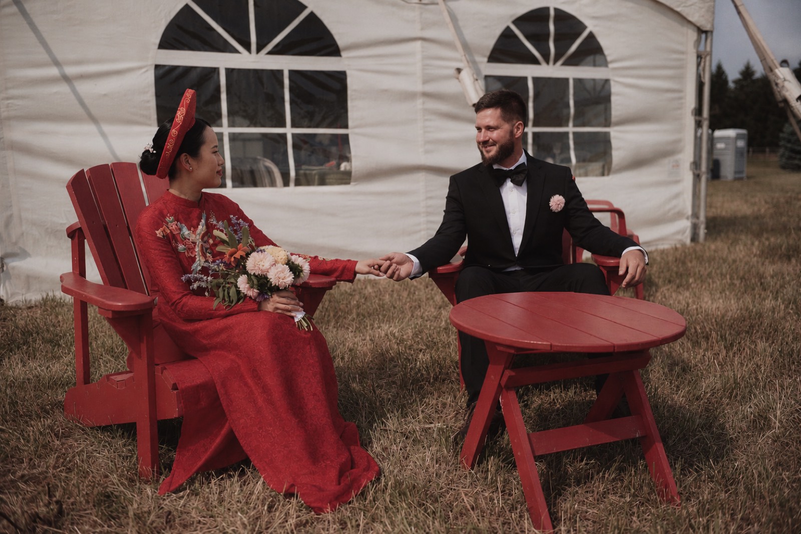 Thu and Simon seated together at their barn reception in Rougemont, Quebec