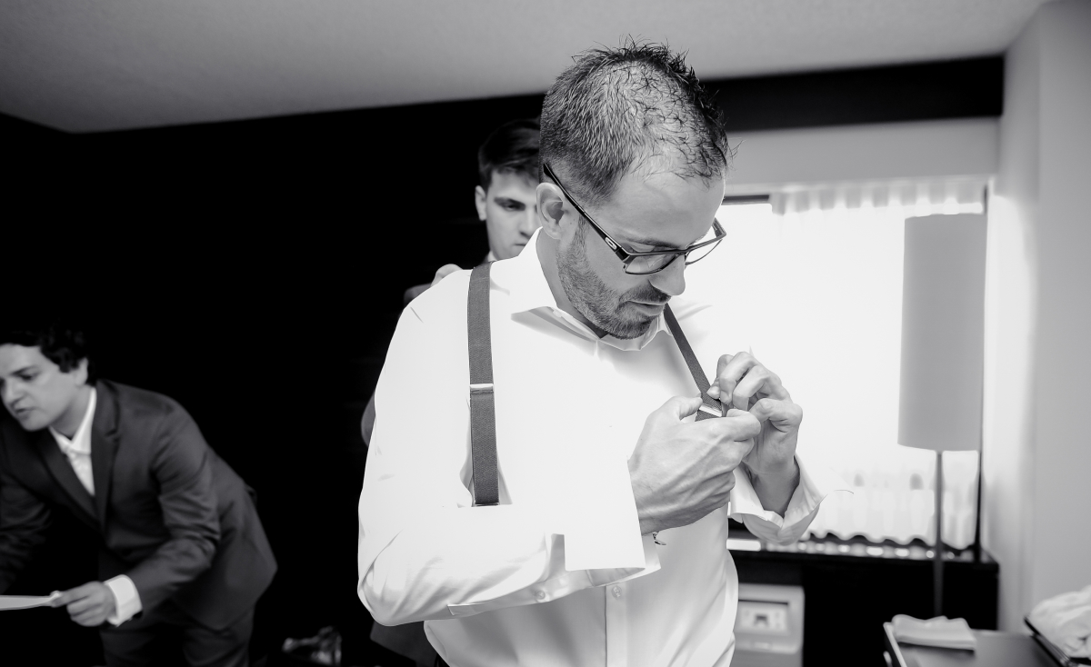 Kenneth getting ready, fastening his suspenders