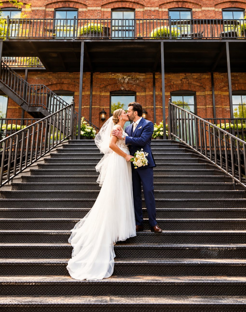 Laurie and Shadi kissing on the stairs at their wedding