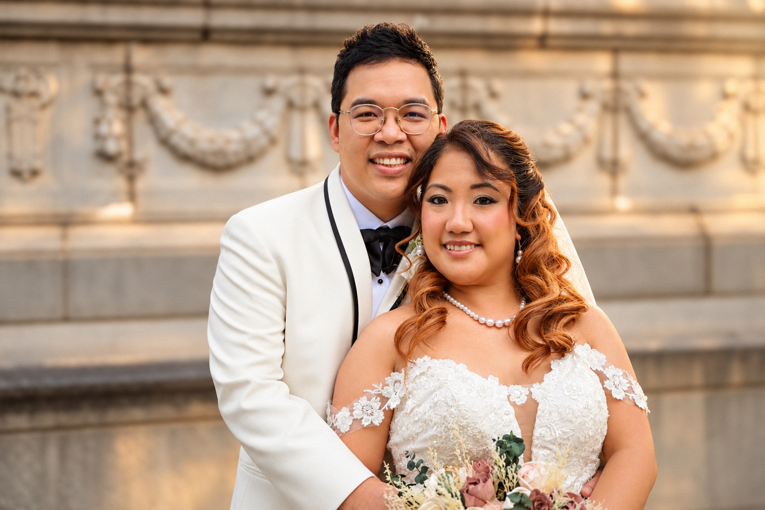 Mae and Daryl in a portrait against the carved stone wall